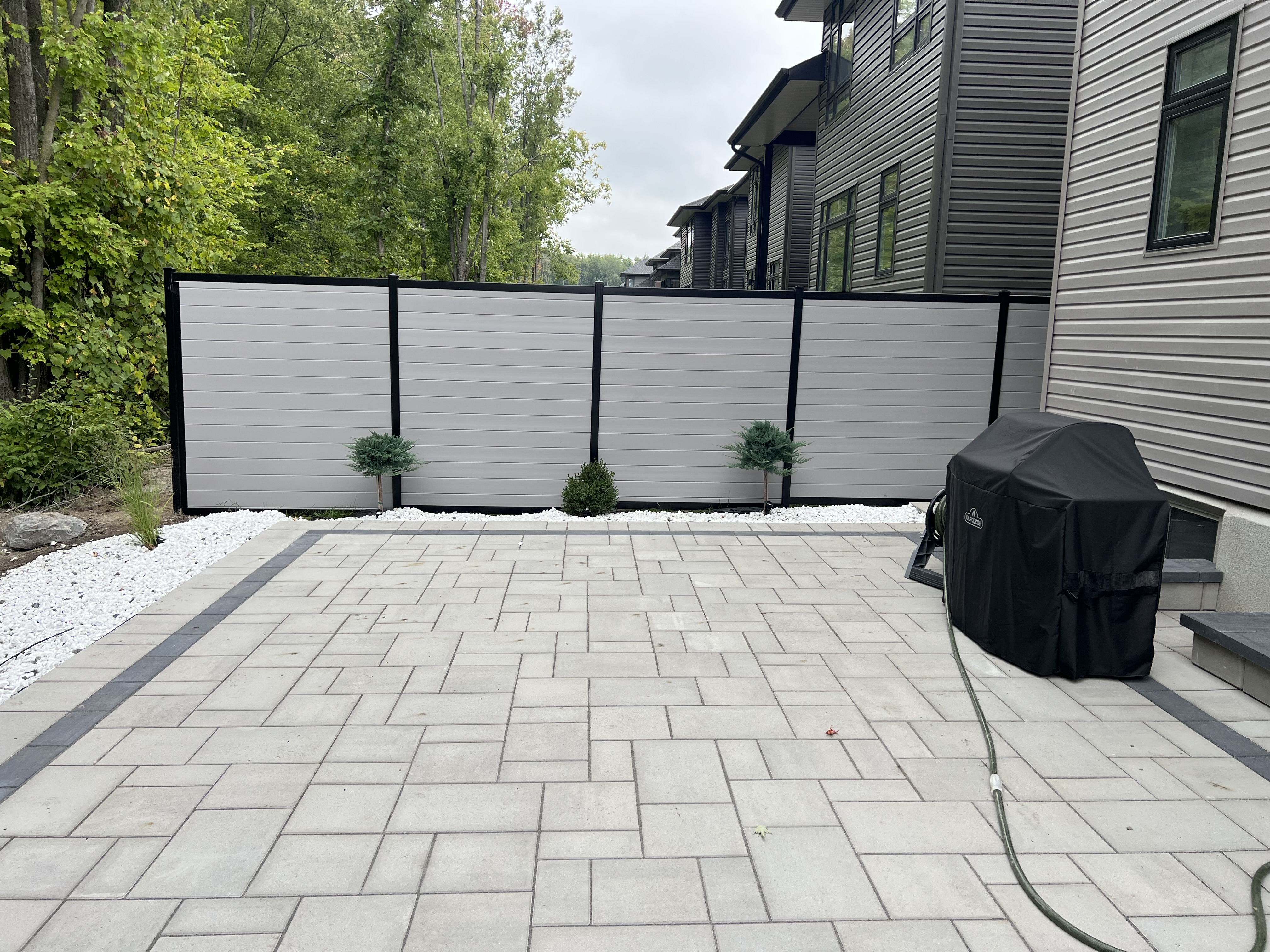 Modern hybrid grey fence with black posts and interlock patio, Ottawa